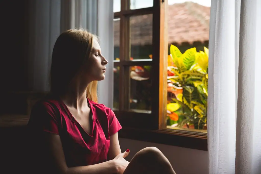 woman looking out window sadly