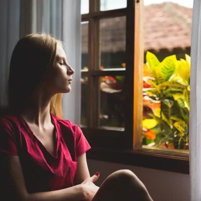 woman looking out window sadly